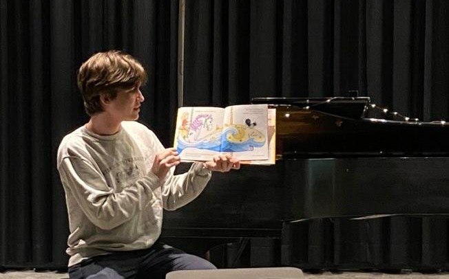 image of Denis reading a children’s story book